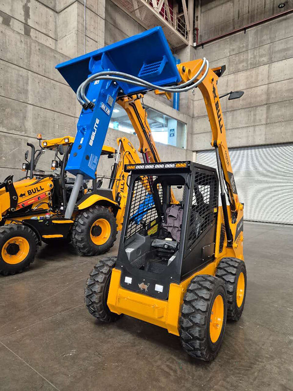 yellow-skid-steer-loader-with-blue-attachment-in-industrial-warehouse